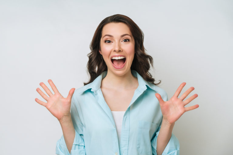 Cheerful positive young woman raising her fists with smiling delighted expression